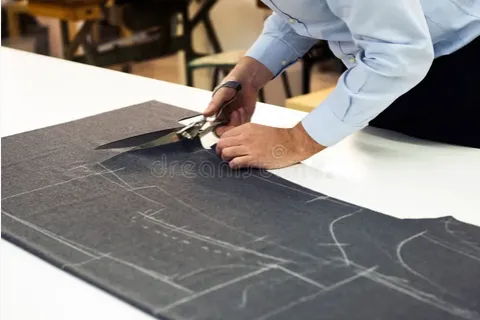 Cutting fabric on the workroom table at Kachins Tailors
